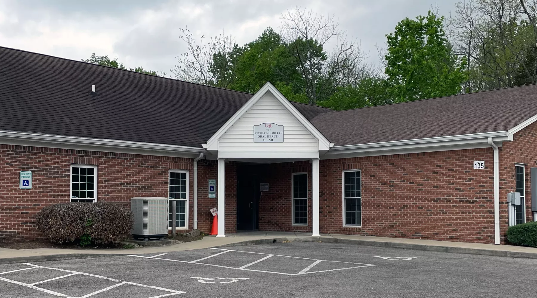 Red brick building with white awning and sign reading "Richard L. Miller Oral Health Clinic"